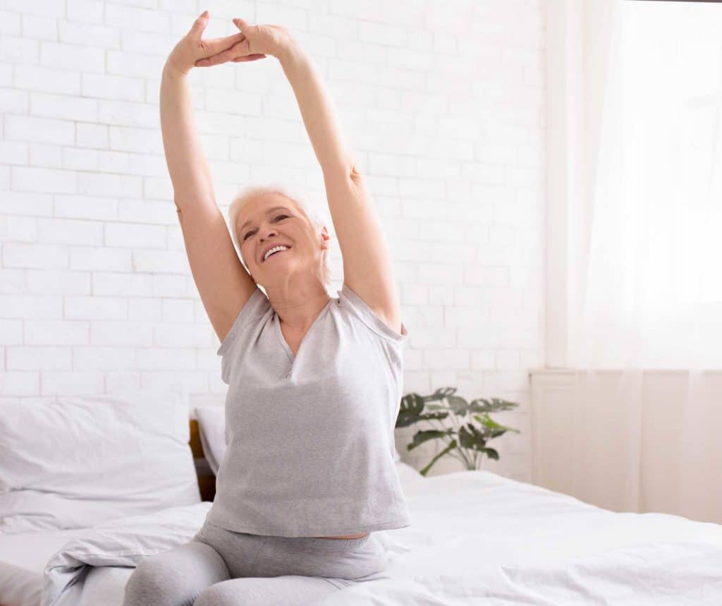 image of elderly woman stretching in the morning at The Legacy at Highwoods Preserve memory care community
