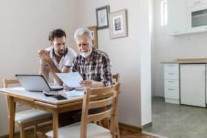 picture of elderly man and family member reviewing finances